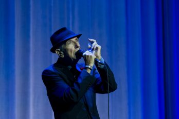 Leonard Cohen performing in front of a blue curtain