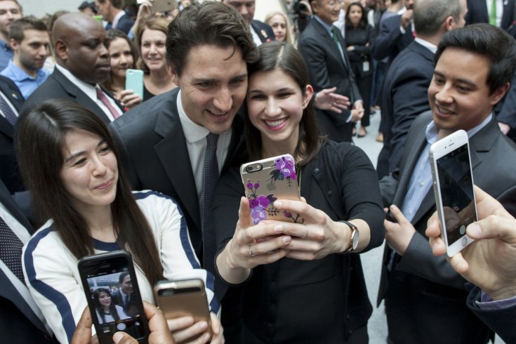 A couple of women taking selfies with justin trudeau