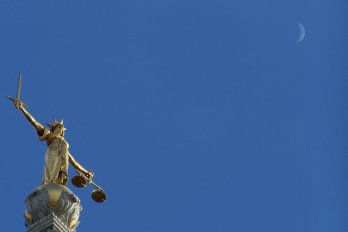 Statue symbolizing justice beneath a crescent moon