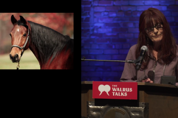 Woman performing for crowd at The Walrus Talks beside photograph of horse