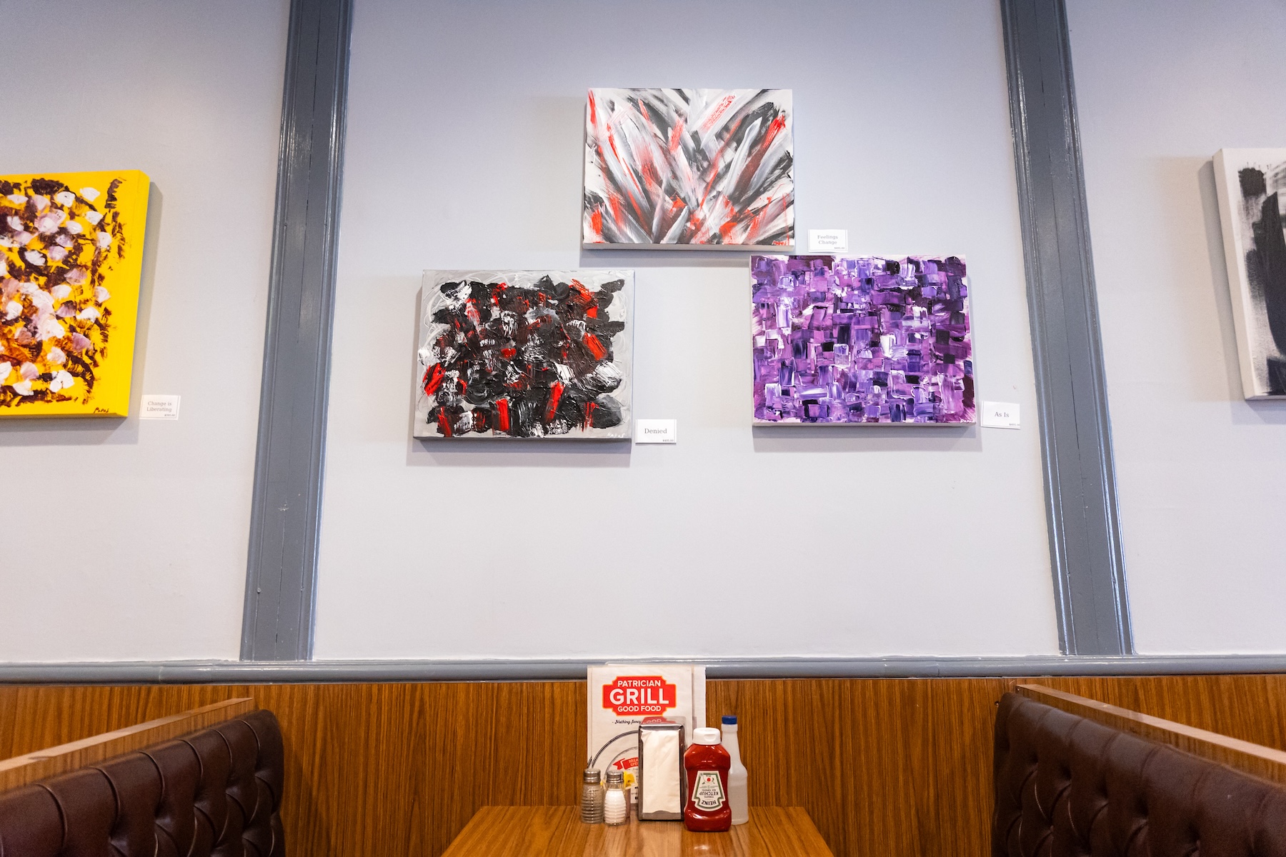 ダイニングテーブルの上に掛けられた3枚の抽象絵画の写真。