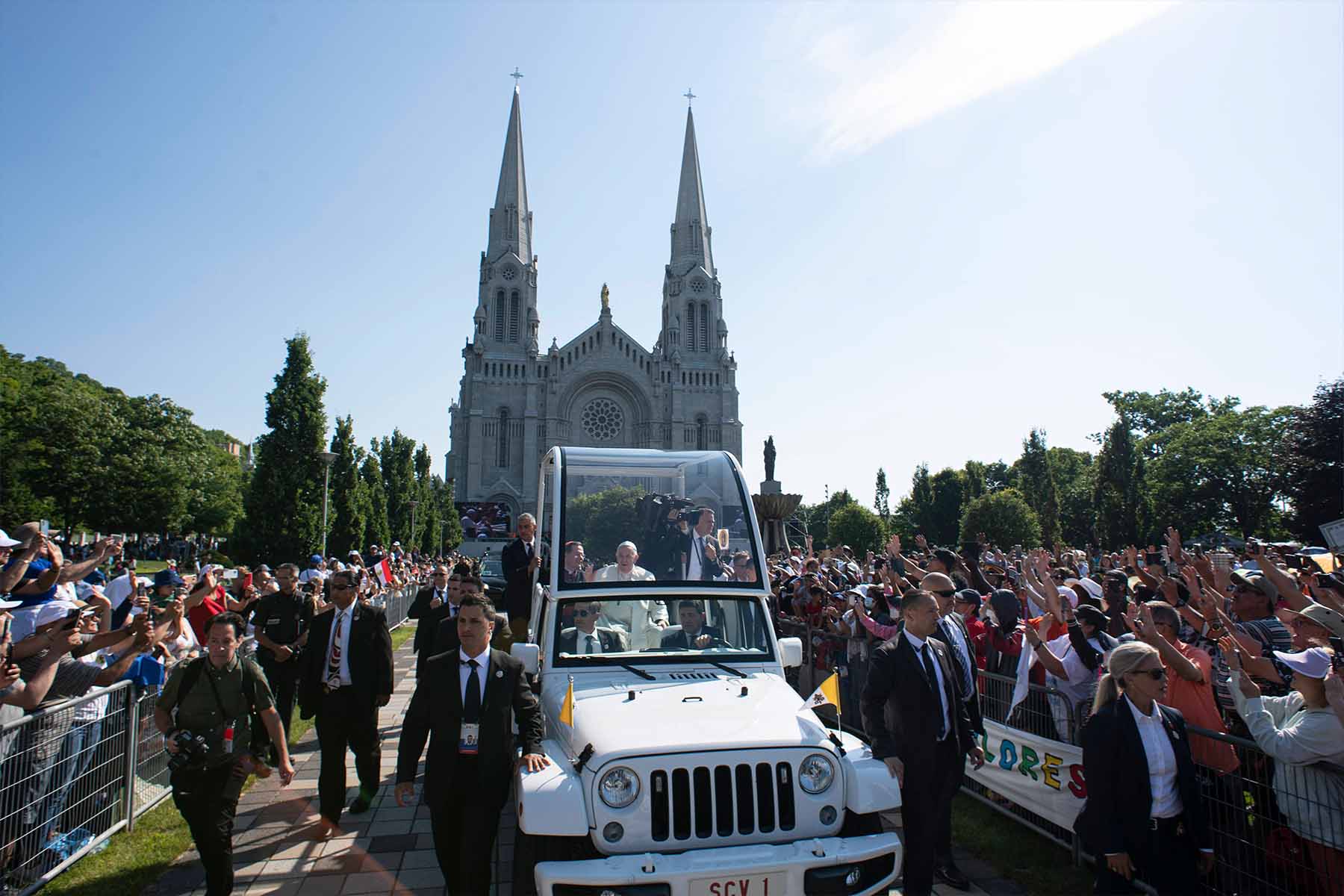 A photo of Pope Francis blessing the crowd outside the Shrine of Sainte-Anne-de- Beaupré, Quebec while riding a Popemobile.