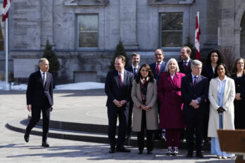 A photo shows Prime Minister Mark Carney walking towards two rows of people comprising some of the ministers in his cabinet after he was sworn in as prime minister