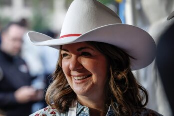 Close-up photo of Alberta premier Danielle Smith smiling and wearing a white cowboy hat.