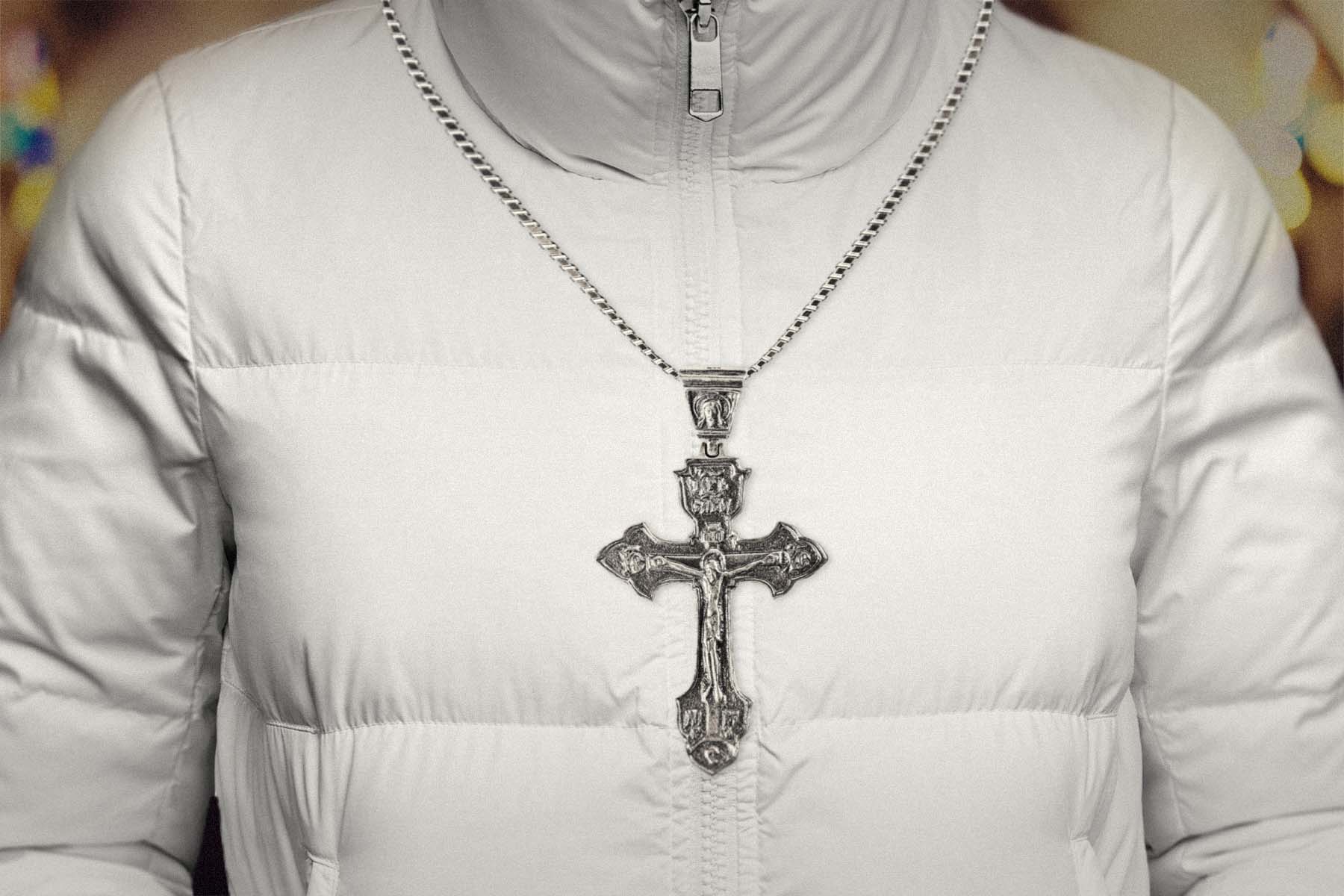 A photo illustration of a person wearing a white puffer jacket and a crucifix necklace.