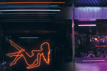 Empty strip club with a neon sign depicting the silhouette of a woman dancing