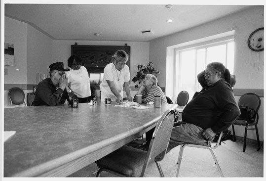 Lillian Moyer serves supper to Edith Carlick in the conference room of the Telegraph Creek band office. Lucy Brown stands at left, next to her husband Orville. Pat Carlick is seated at right.