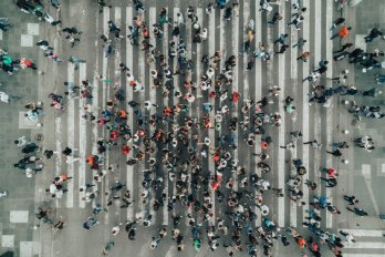Aerial view of a dense crowd of people crossing the street at a major crosswalk.