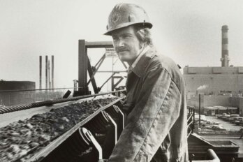 A black-and-white photo of a man in a hard hat at an oil rig