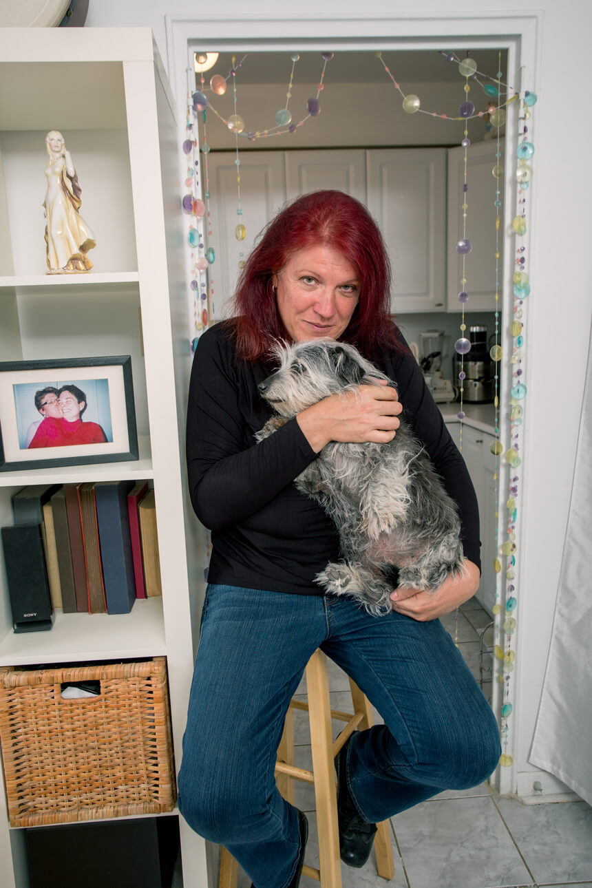 Photograph of a person with mid-length red hair holding a dog in their arms.