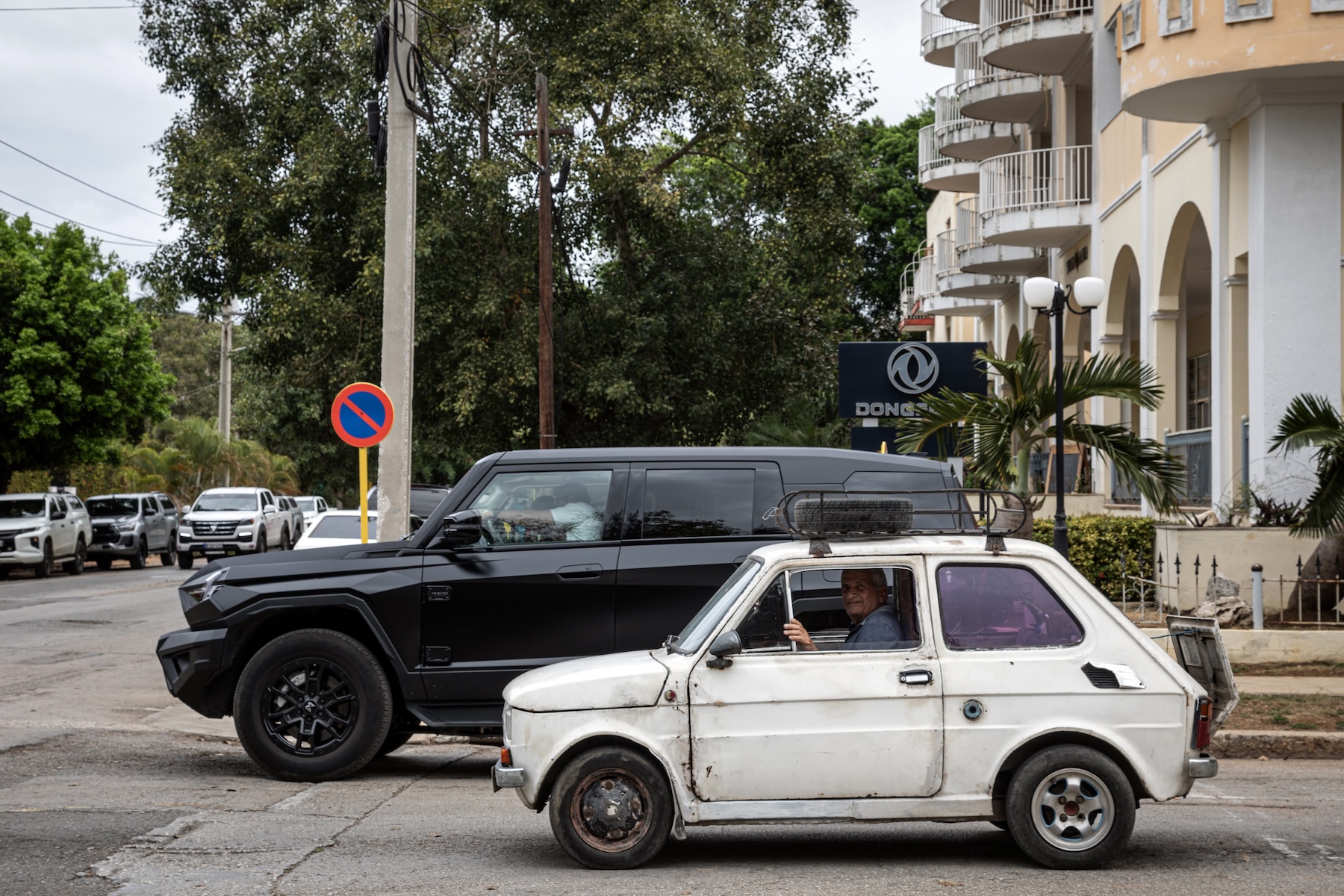Photo of a big black SUV next to a small white car on the road.