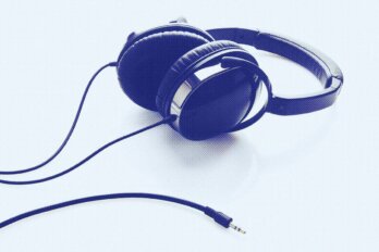 A photo illustration of an unplugged set of over-the-ear headphones with a blue tint and halftone overlay.