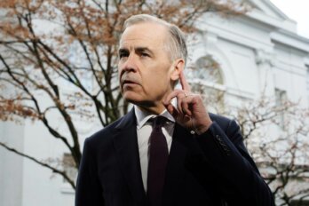 Photo of Prime Minister Mark Carney with a finger raised to his ear.