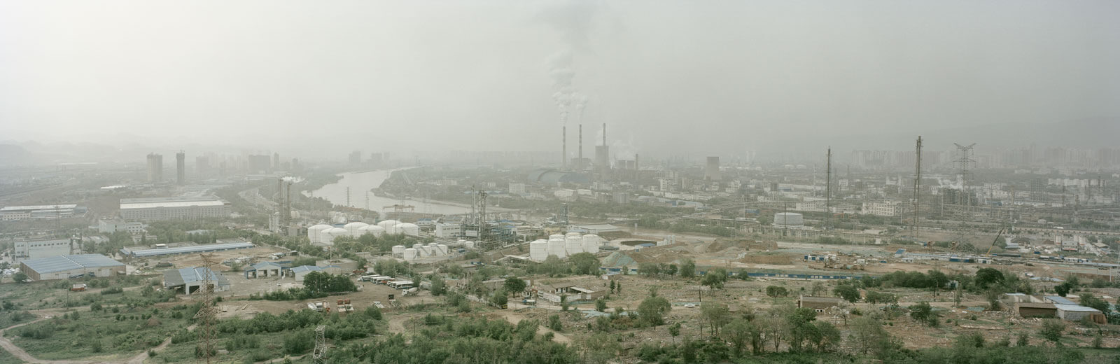 A wide view of the city of Lanzhou, which is very industrial with a hazy sky.