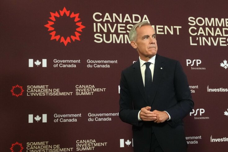 Photo of Prime Minister Mark Carney in front of a brown wall filled with logos as part of the Canada Investment Summit.