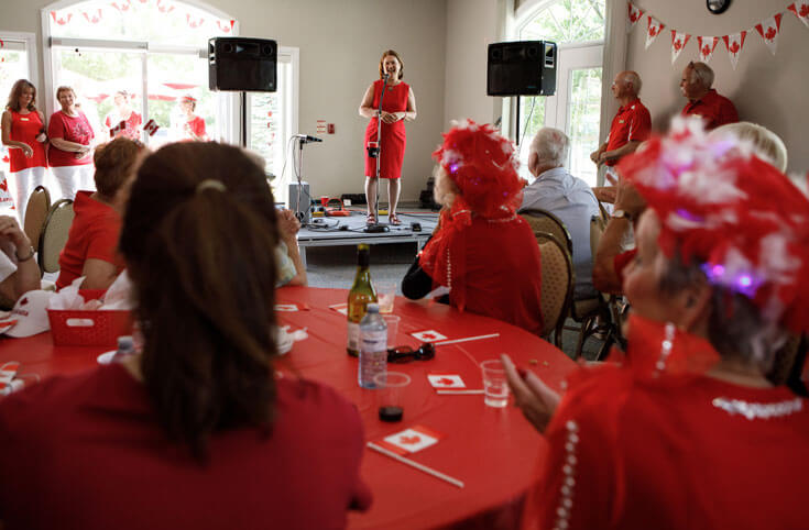 Jane Philpott stands on a podium as onlookers dressed in red watch.