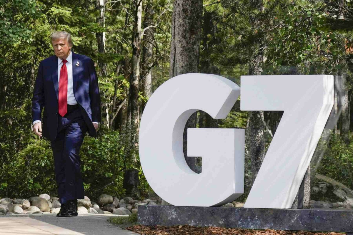 Photo shows US president Donald Trump walking past a G7 sign