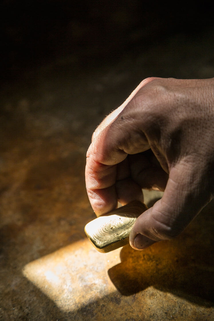 Closeup of a hand holding a rectangular gold bar.