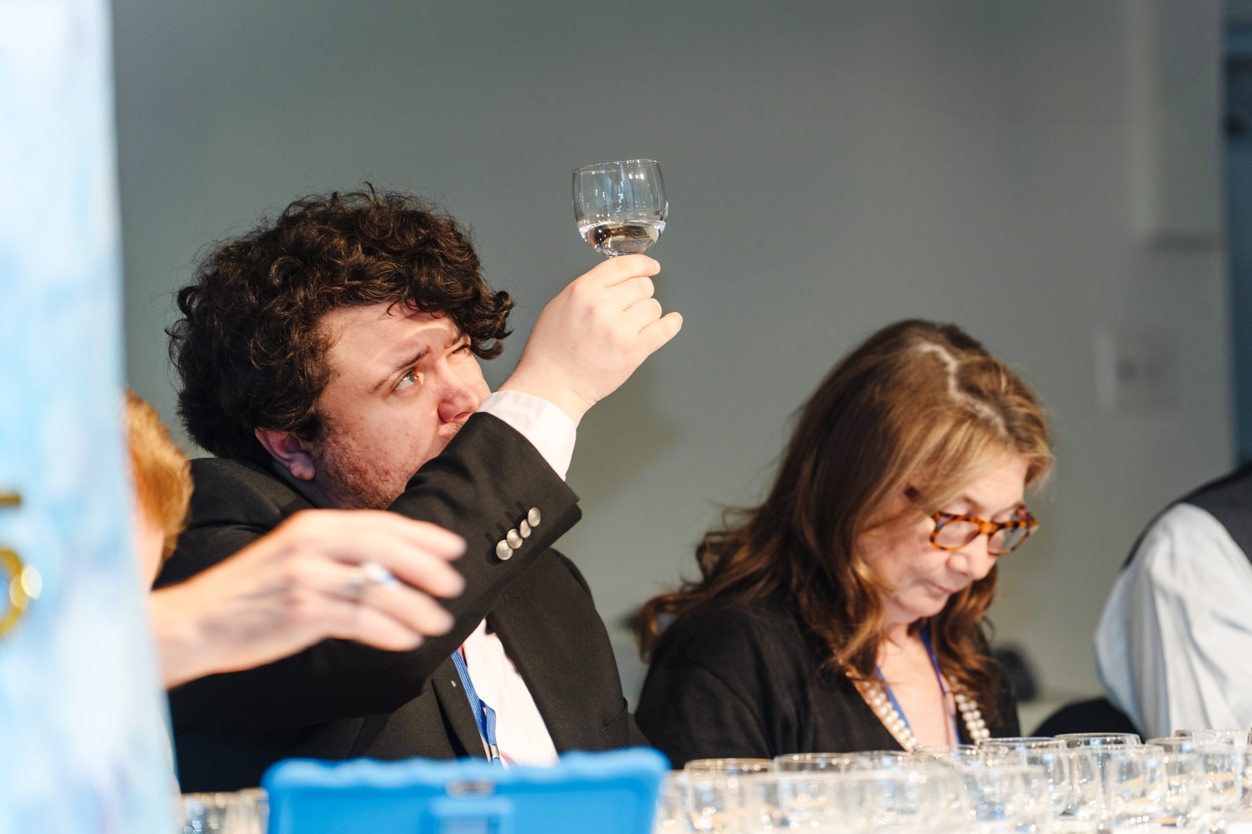 A man holds up a small glass of water to the light