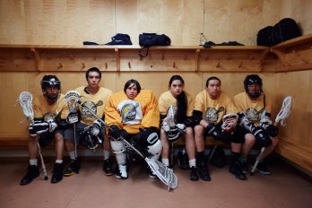 A group of lacrosse players sitting on a bench.