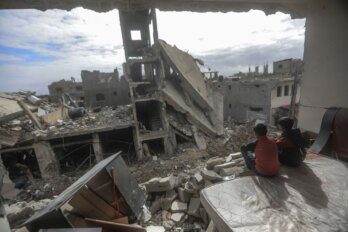 A photo of Palestinian children sitting in a destroyed house while looking at ruins on November 28, 2023 during the temporary ceasefire between Israel and Hamas, in the village of Khuza'a near the border fence between Israel and the southern Gaza Strip.