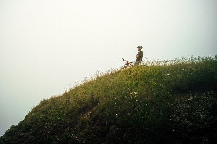 A cyclist looks out on a cliff