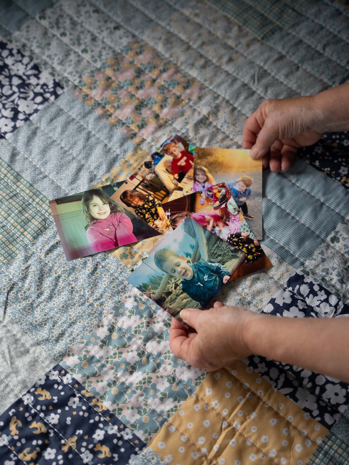 Image of five printed-out photos depicting a young girl and boy arranged on top of a floral, checkered quilt.