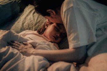A woman kisses a sleeping child on the forehead