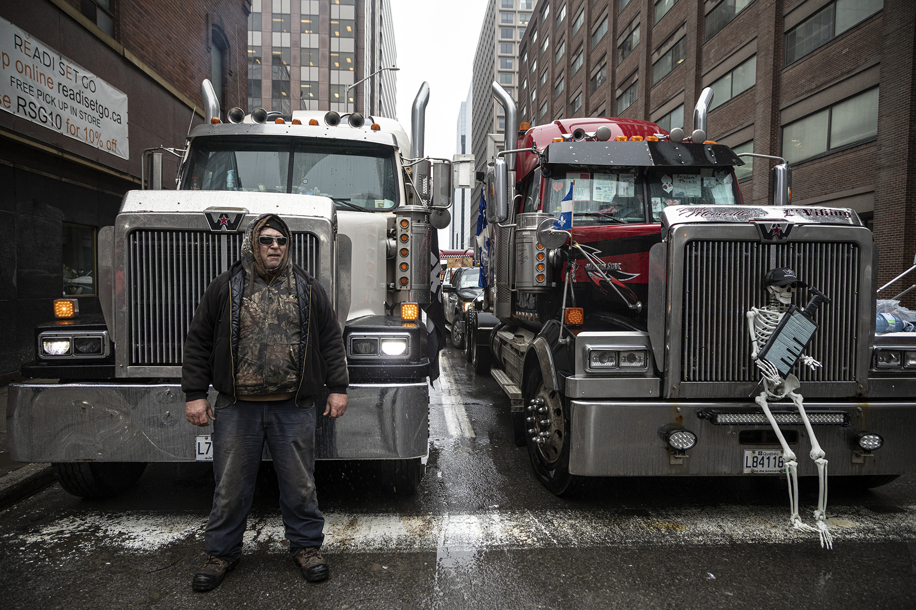 A protester stands before a truck on the corner of Slater and Bank street in Downtown Ottawa