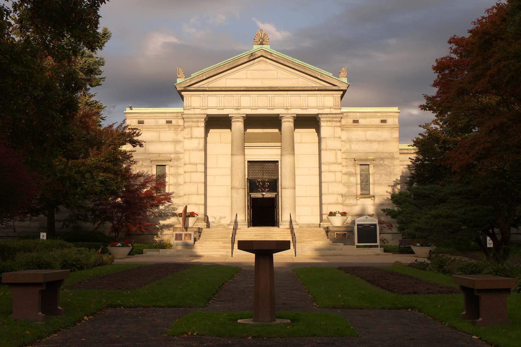 A photo of the mausoleum and chapel at Mt. Pleasant Cemetery in Toronto, cast in a ray of light with dark clouds behind it.