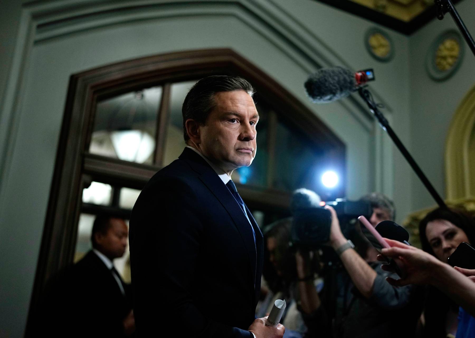 Photo of opposition leader Pierre Poilievre with press microphones being pointed at him.
