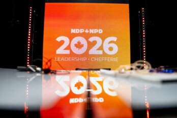 Photo of the NDP leadership debate stage. An orange banner reads NDP 2026 leadership.