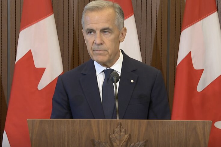 A photo of Prime Minister Mark Carney standing at a lectern, with the Canadian flag in the background