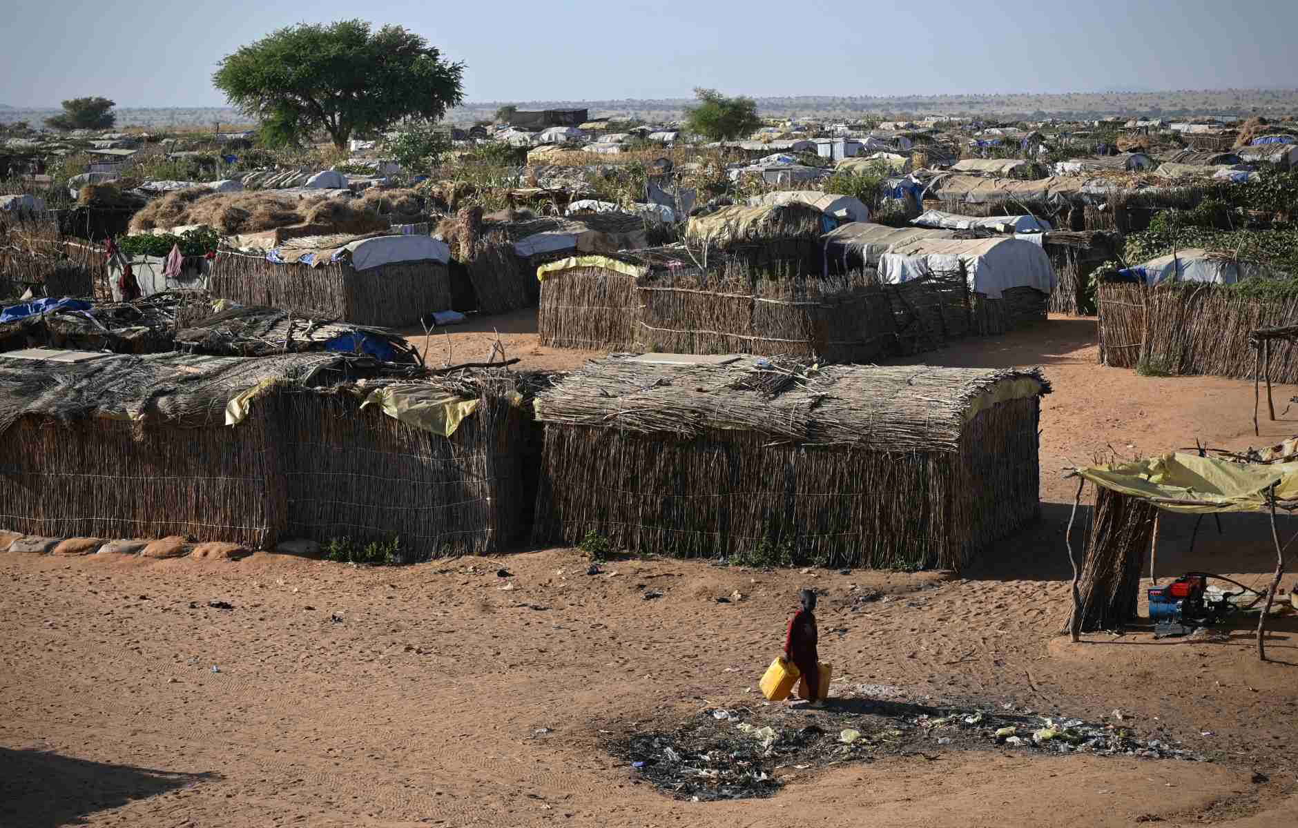 Photo of a village comprised of huts constructed using sticks and thatched roofs.