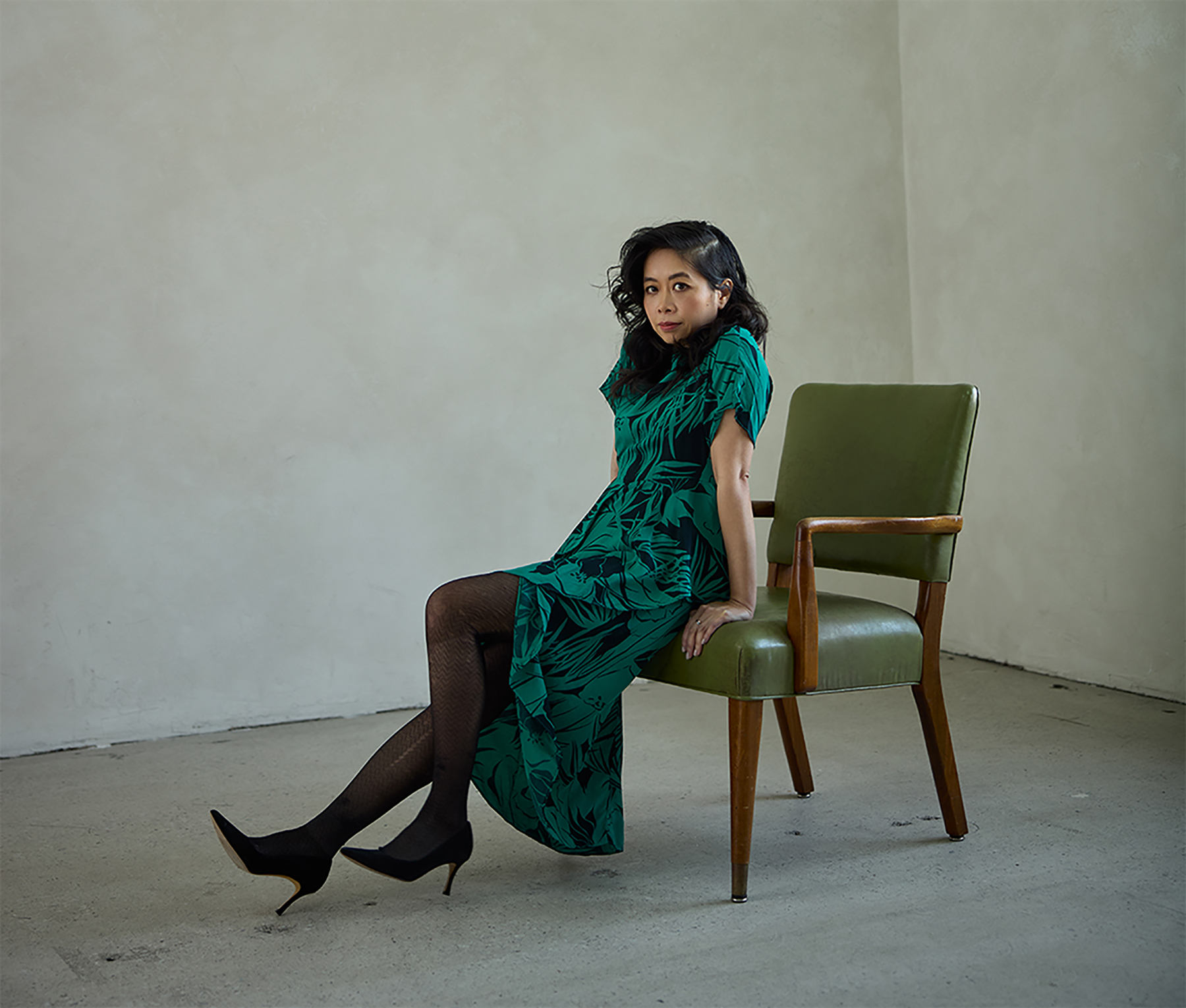 Picture of author Souvankham Thammavongsa sitting on a chair and wearing a green dress.