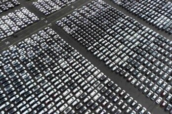 Overhead image of a parking lot filled with white cars in a grid.