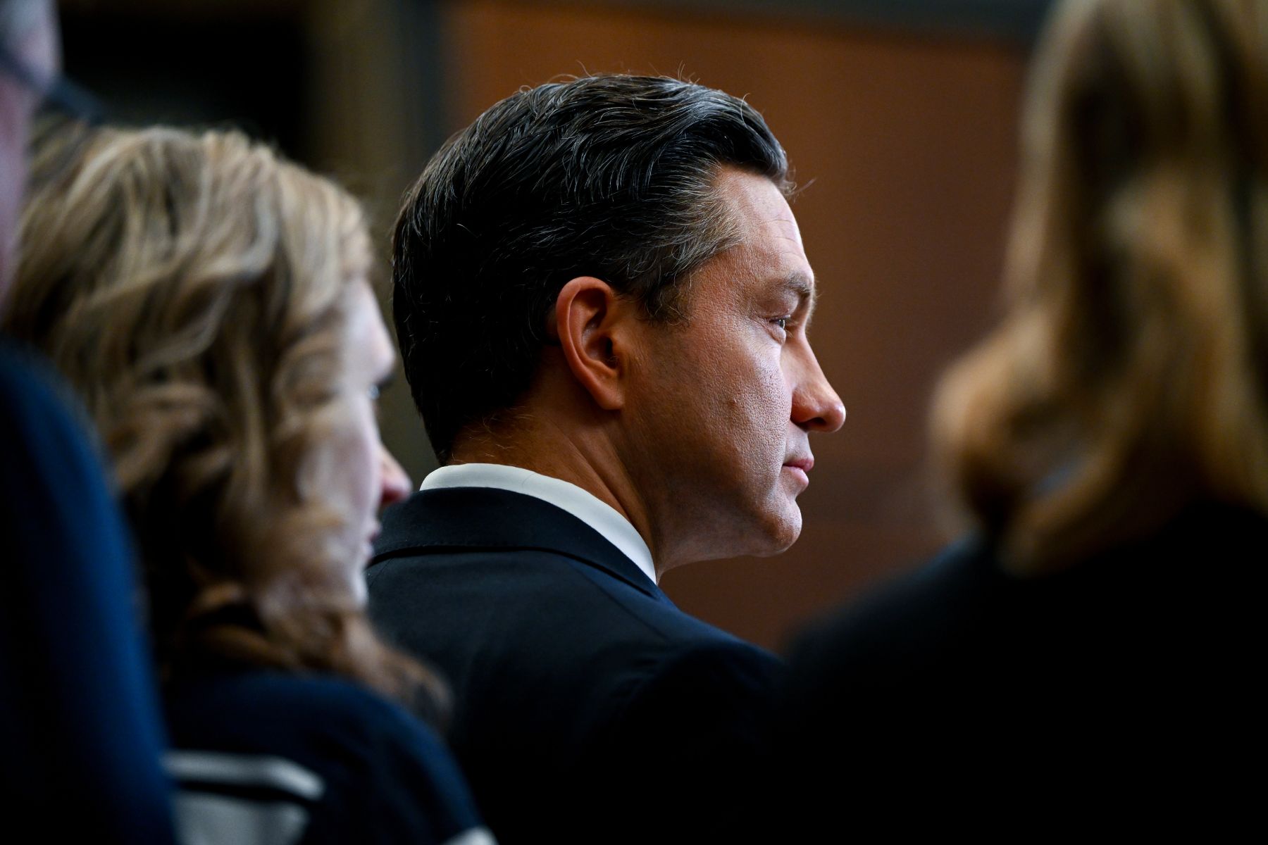Photo of Pierre Polievre in profile taken from behind him with other people crowding either side of the image.