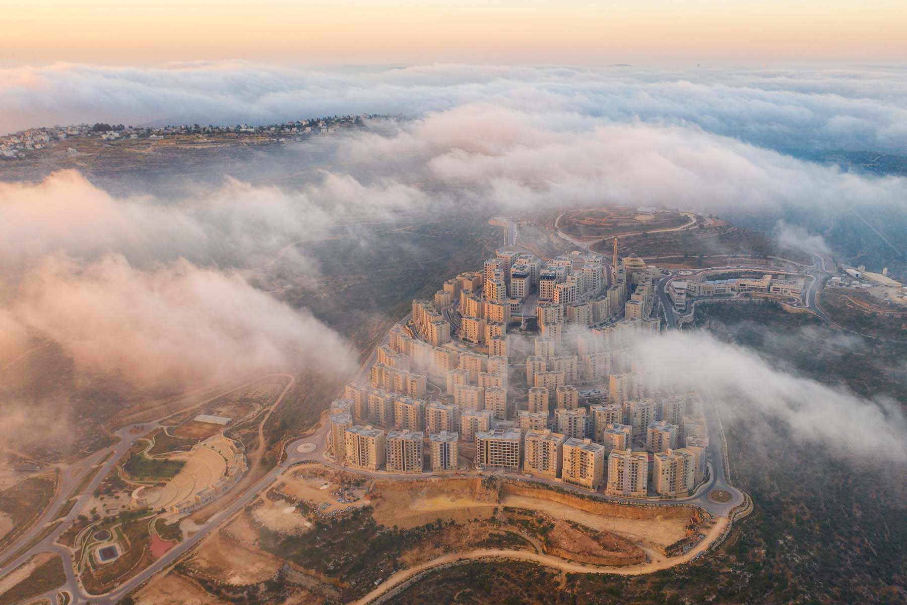 An aerial photo of the tall apartments towers of Rawabi, shrouded in clouds, in the West Bank.