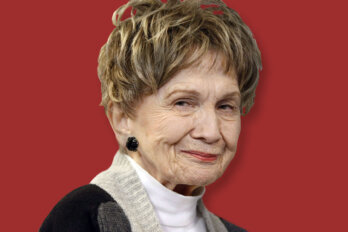 A photo of Alice Munro against a full red backdrop