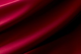 Ruby red fabric rippling down to the bottom left corner of the image in big folds.