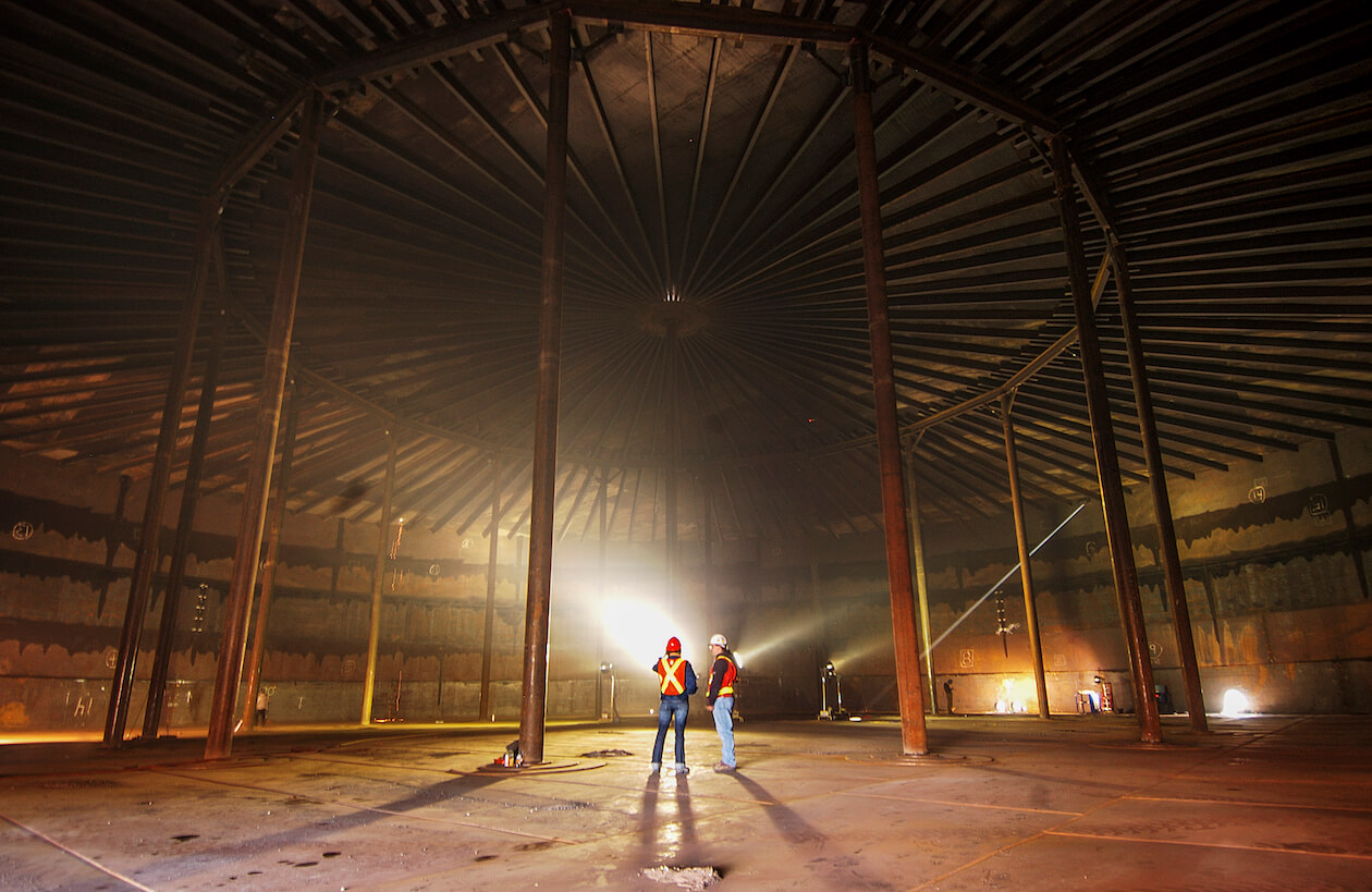 Two men stand inside an empty fuel container at Yellowknife's tank farm.