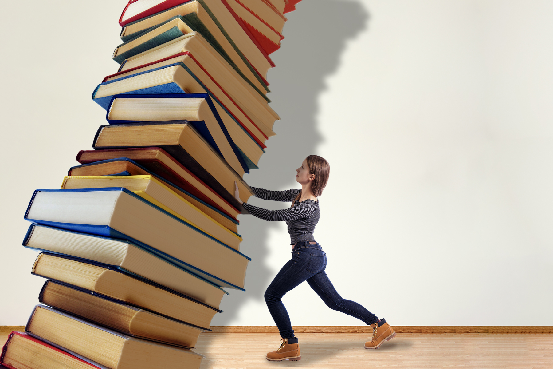 In a photo illustration, a woman tries to hold up an enormous tower of books looming and leaning over her.