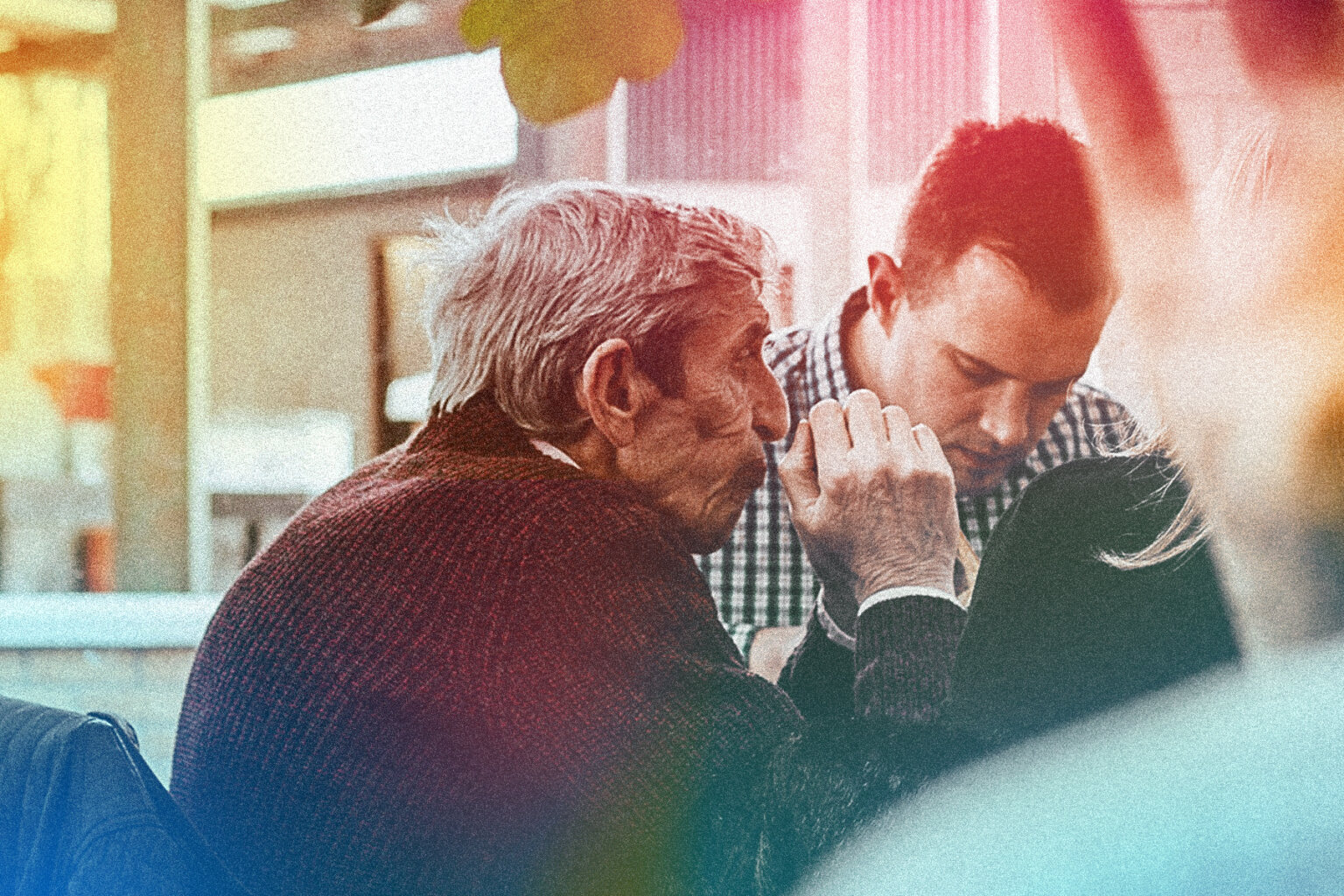 Photo shows an old man and a young man seated together