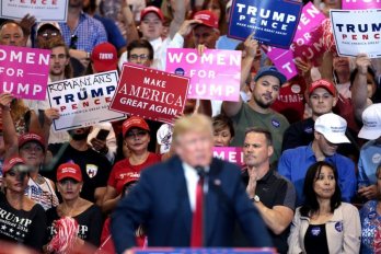 Crowd displays political campaign signs behind president donald trump