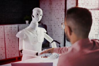 Man shakes hands with a robot in an office setting.