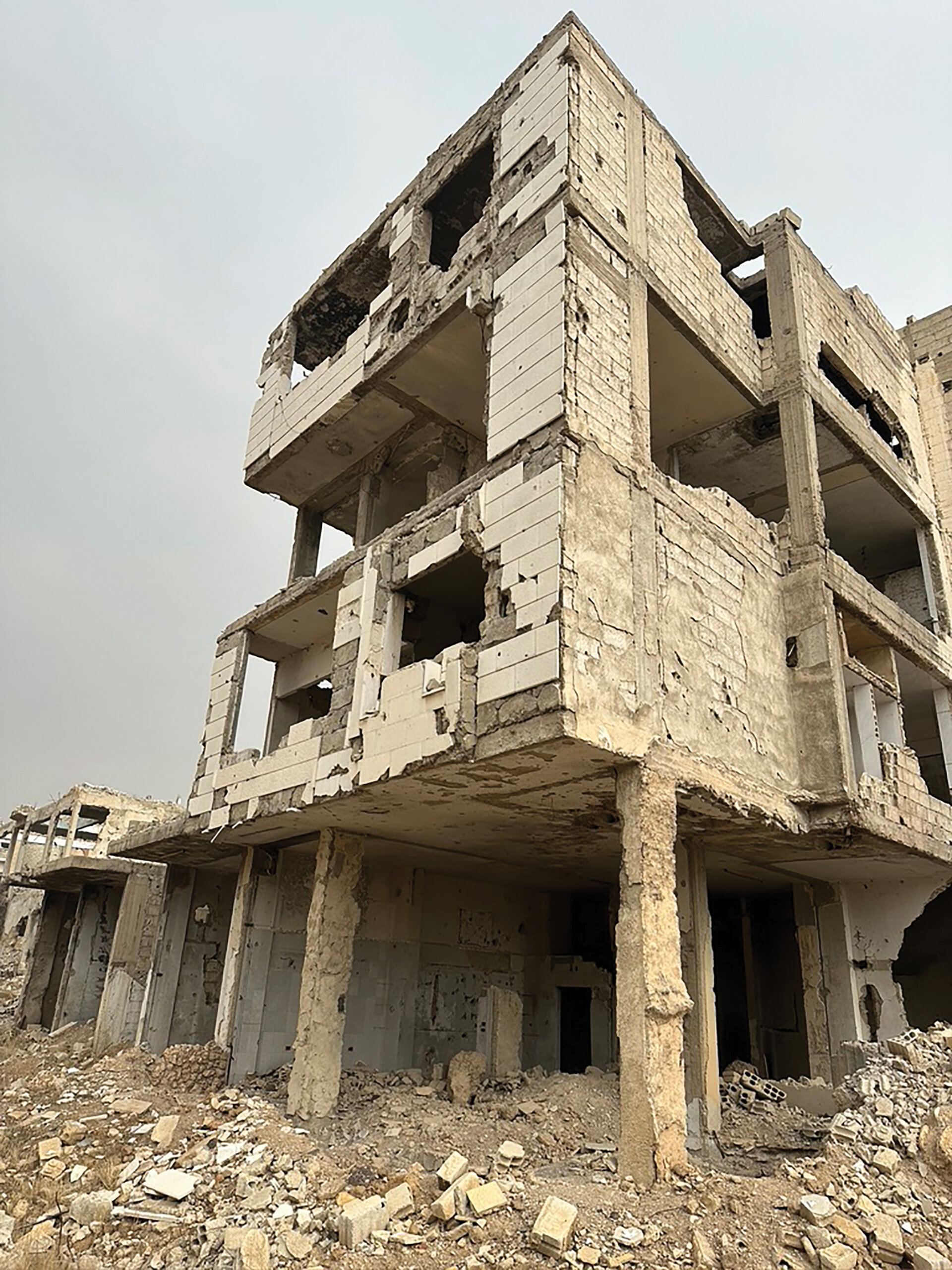 A photograph of the concrete shell of a damaged building against a grey sky