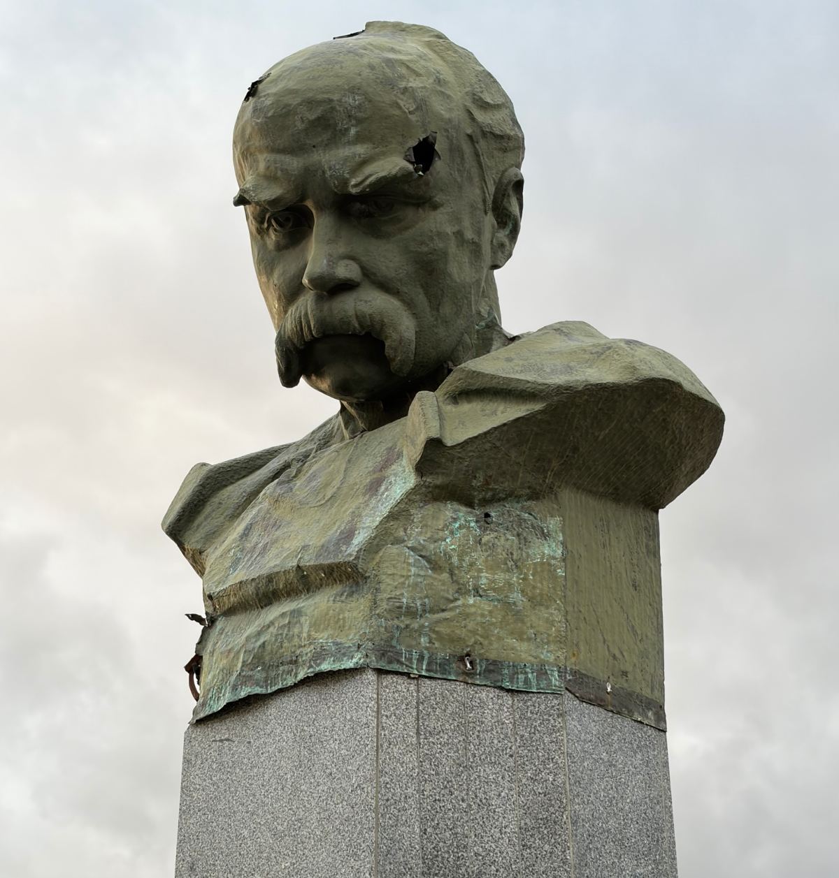 A photo of a monument, a stone bust of man with a moustache