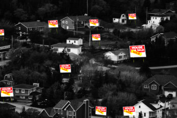 A group of houses in a small town with "for sale" signs