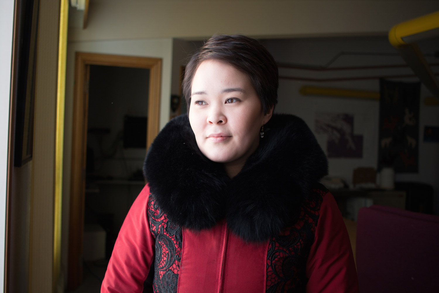 A woman stands inside her home.