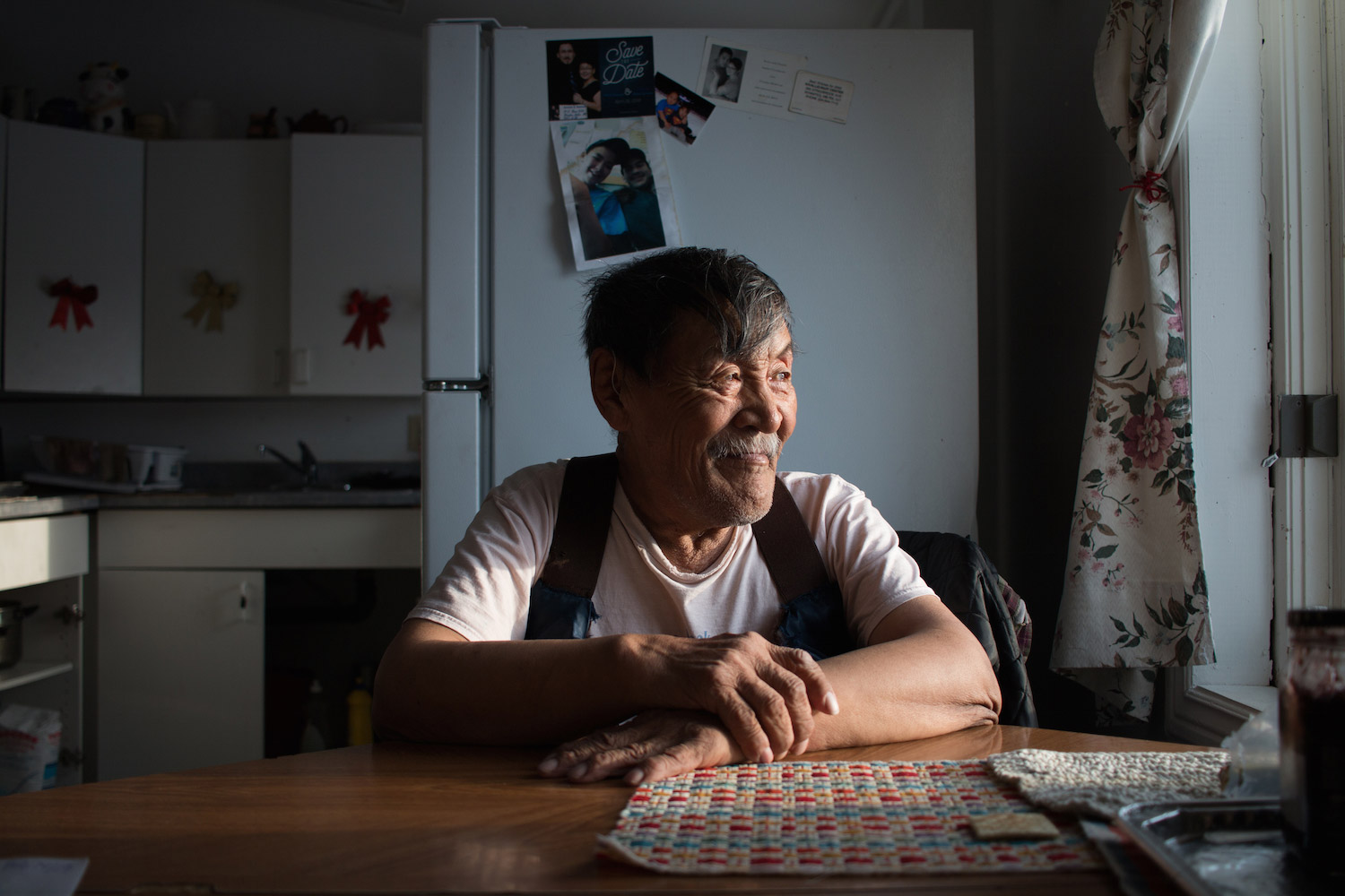 A man sits at a table staring out the window